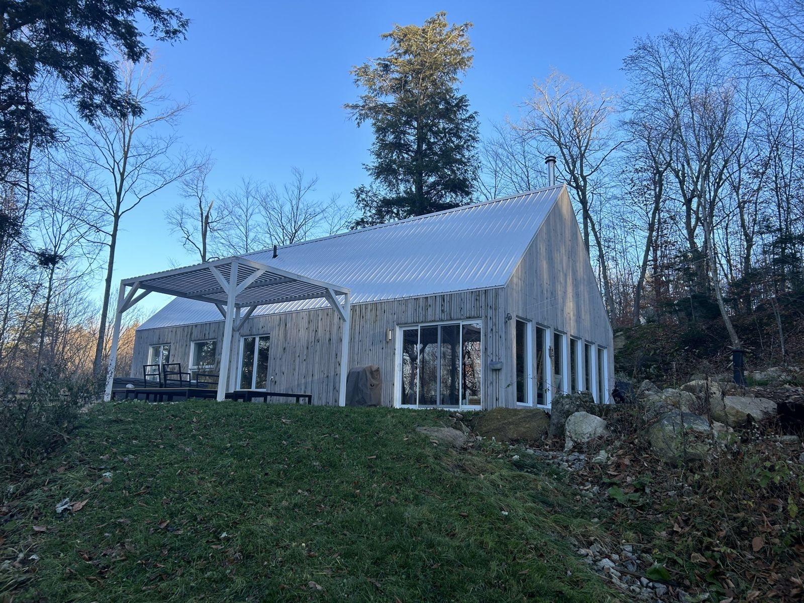 Maison au bardage de bois et toiture métallique, en forêt